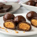 Finished Butterfinger balls coated in chocolate and arranged on a plate.