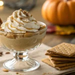 A serving of pumpkin fluff in a dessert cup with graham crackers.